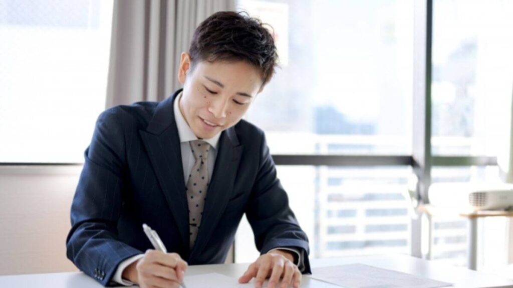 真剣にメモ書きをするスーツ姿の若い男性