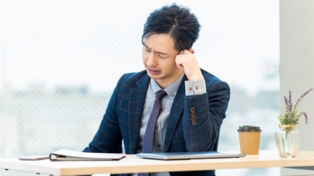 肘をつき悩むスーツ姿の中年男性