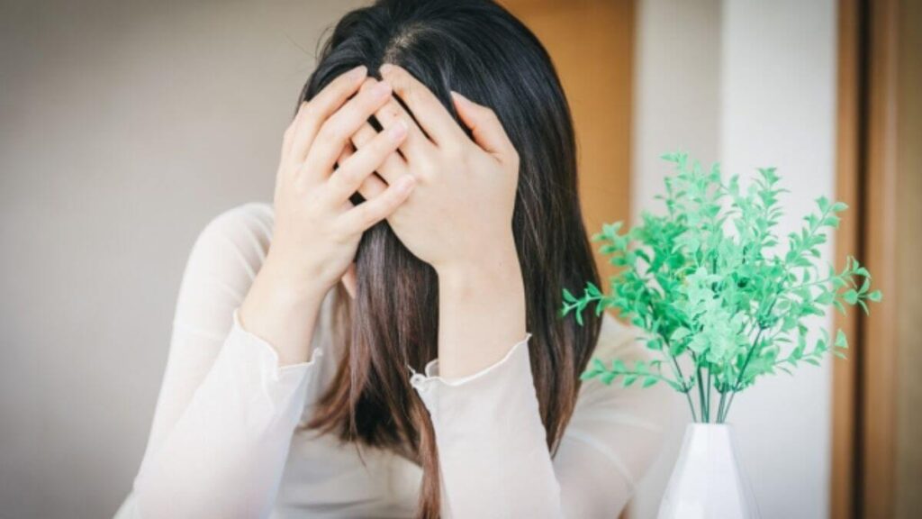自室で頭を抱え悩む若い女性
