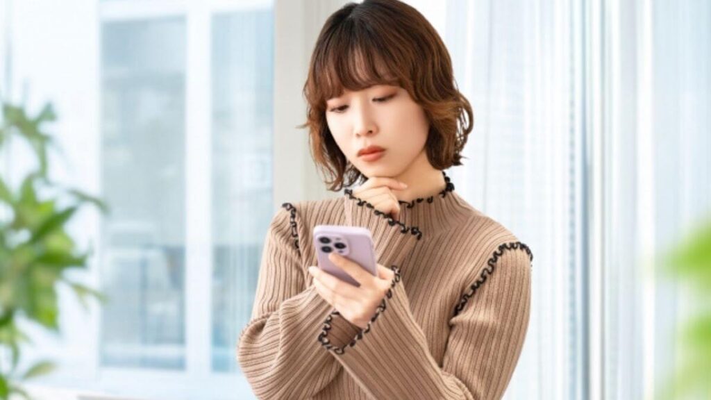 スマホを操作しながら悩む若い女性