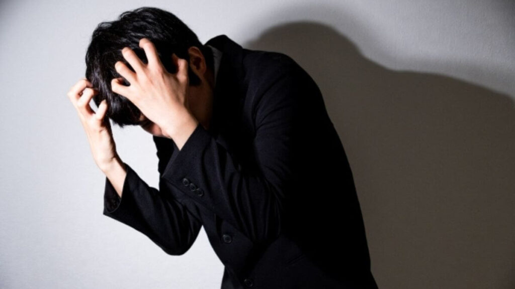 部屋で頭を抱え落ち込みう男性