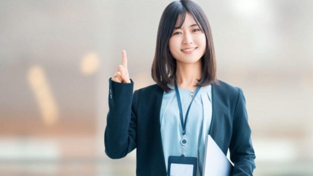 指をかざし微笑む若いスーツ姿の女性