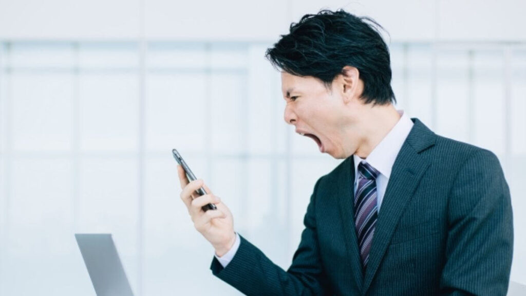 スマホに向かって怒鳴るスーツ姿の男性