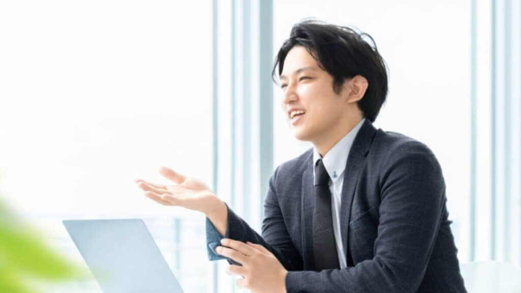 パソコンを持ち説明するスーツ姿の男性