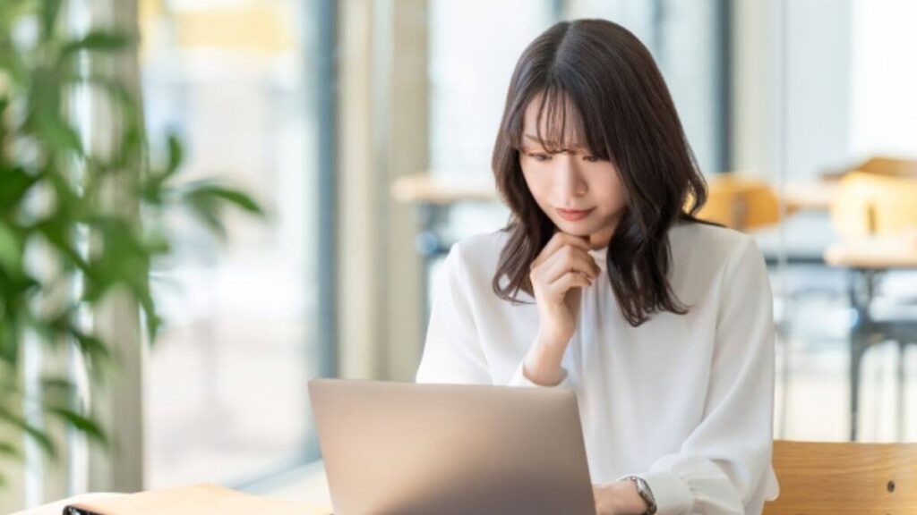 パソコン作業をしながら悩む女性