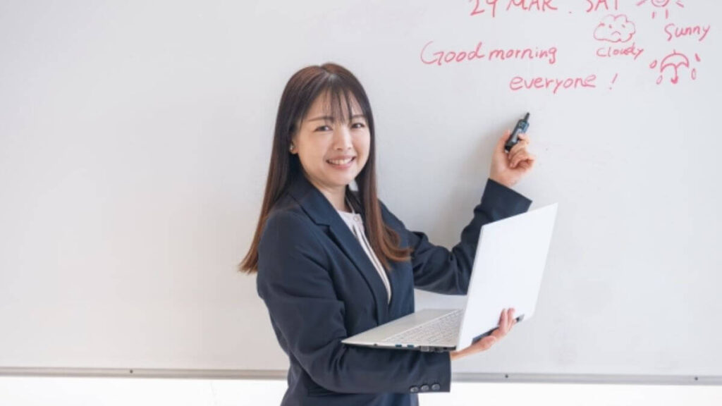パソコンとホワイトボードを使い説明する女性