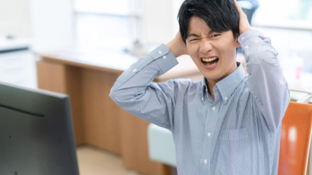 家で頭を抱える若い男性